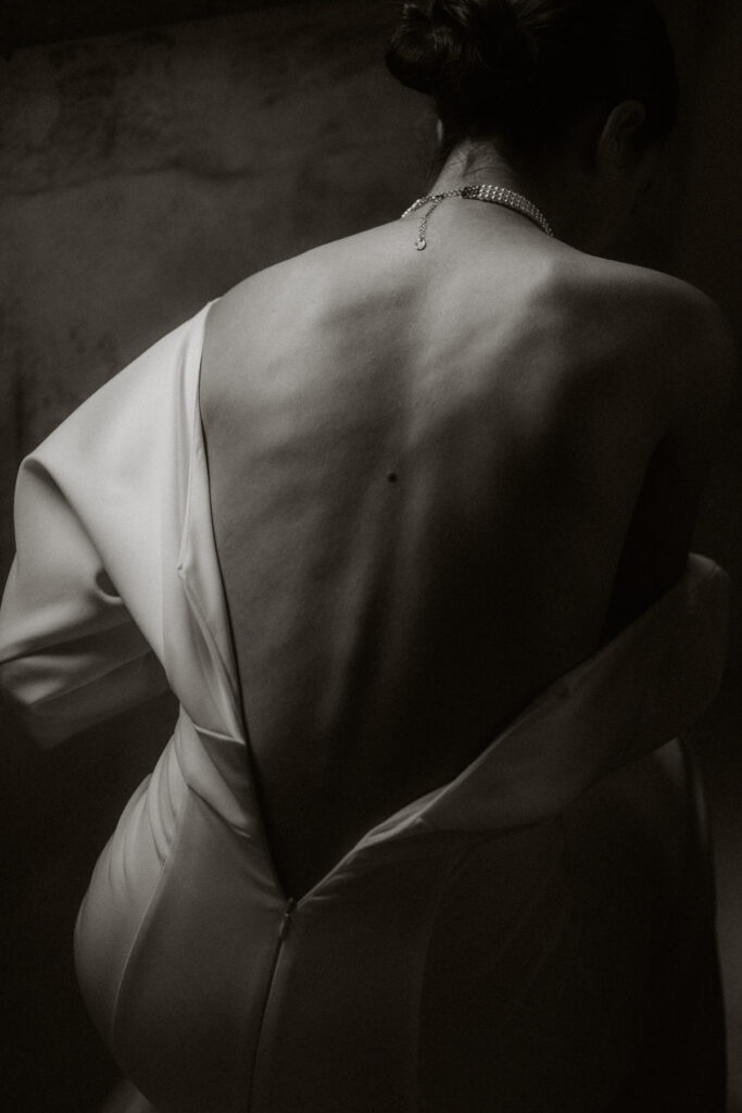 photo noir et blanc du dos nu d'une mariée en train d'enfiler sa robe - photographe mariage à Bordeaux